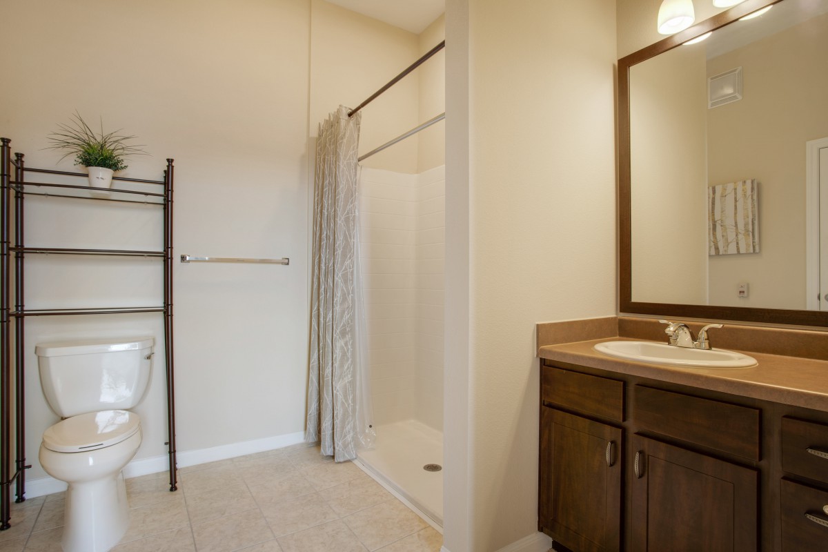 A simple bathroom with a shower, vanity sink, and towel rack.