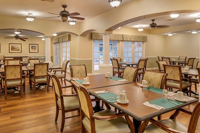 A tastefully decorated dining room with wooden tables and chairs, featuring elegant lighting and large windows.