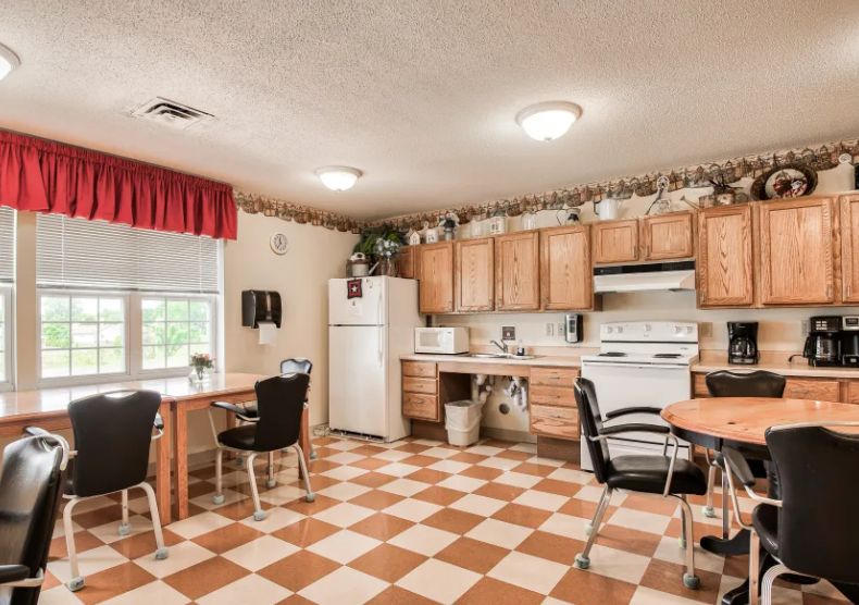 A cozy kitchen with a checkerboard floor, wooden cabinets, and a dining area.