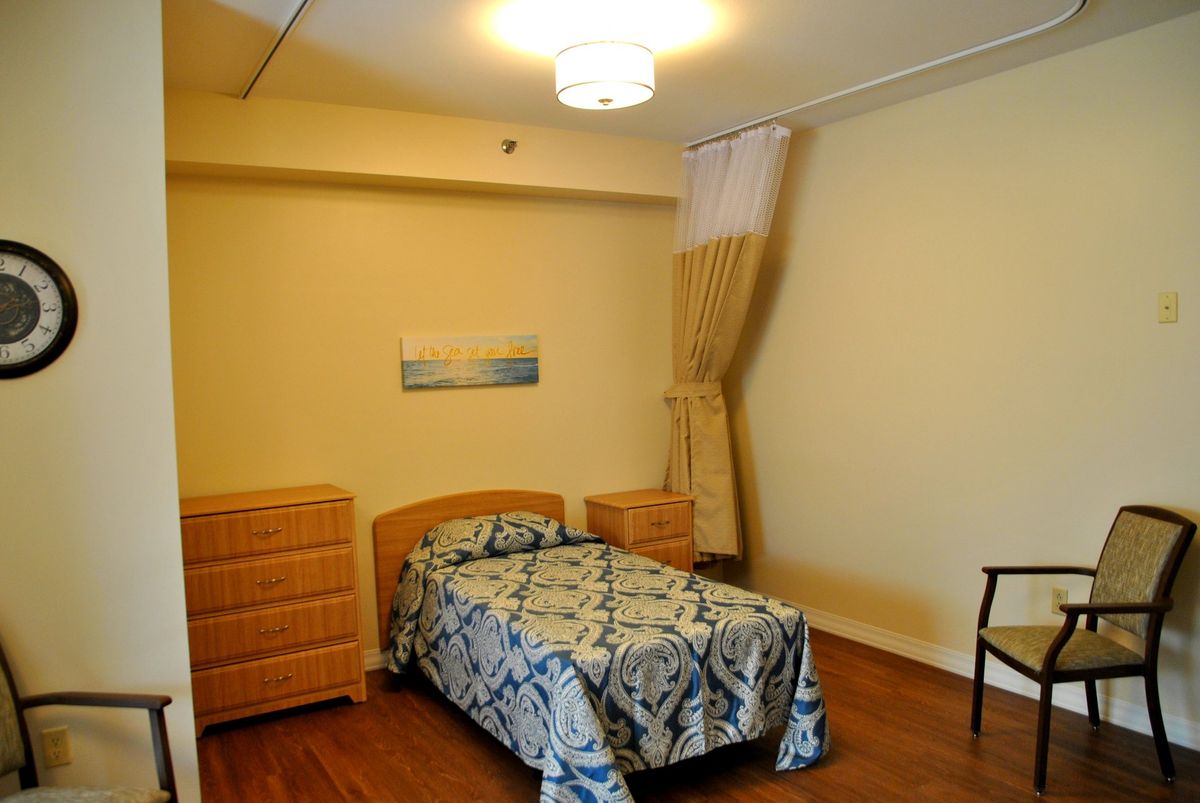 A simple bedroom with a single bed, two dressers, and curtains.