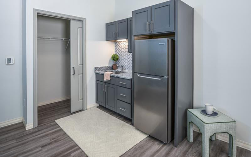 Modern kitchen with gray cabinets and stainless steel refrigerator.