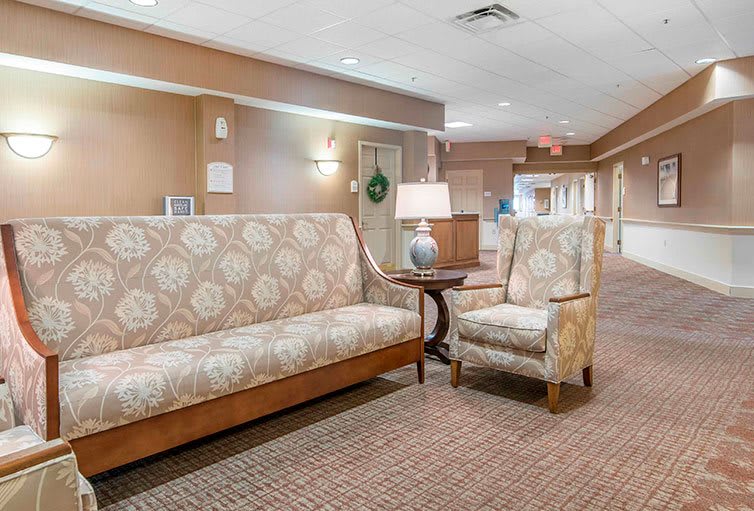 A cozy lobby area featuring a patterned sofa and chair with a lamp on a side table.