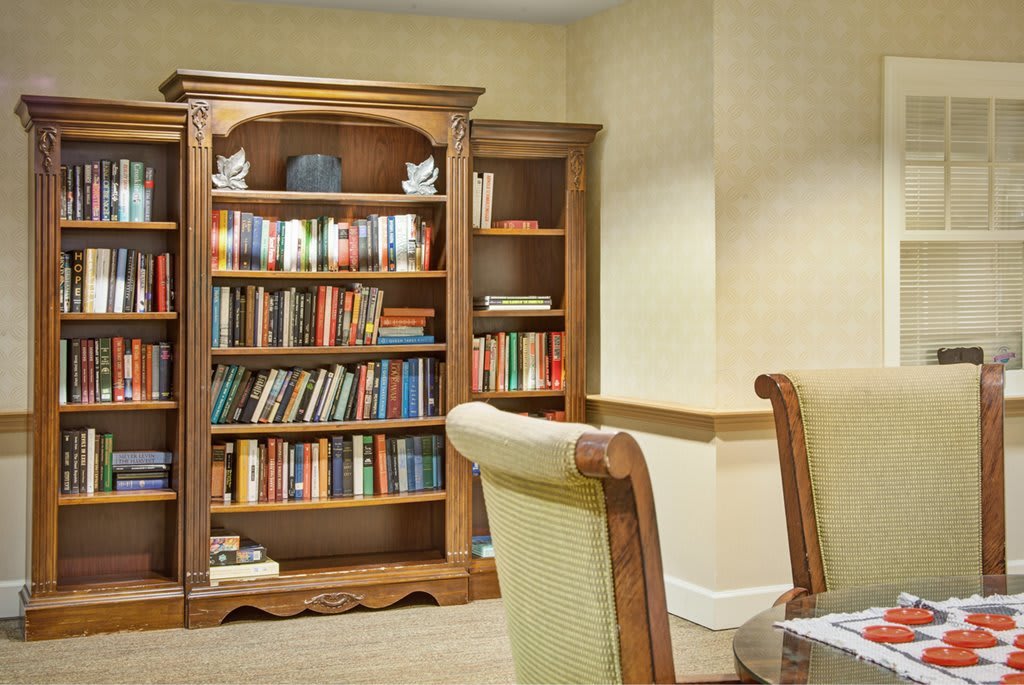 A cozy library corner with a wooden bookshelf filled with books and comfortable chairs.
