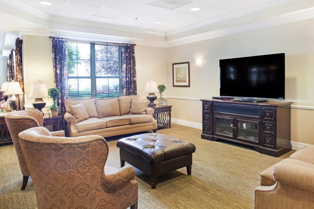 A cozy living room with a sofa, armchair, coffee table, and television.
