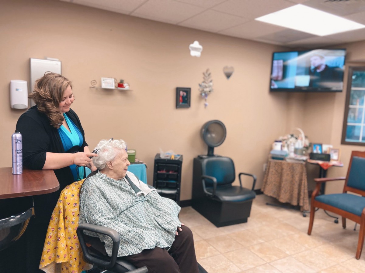 A hairstylist attending to an elderly woman in a cozy hair salon.