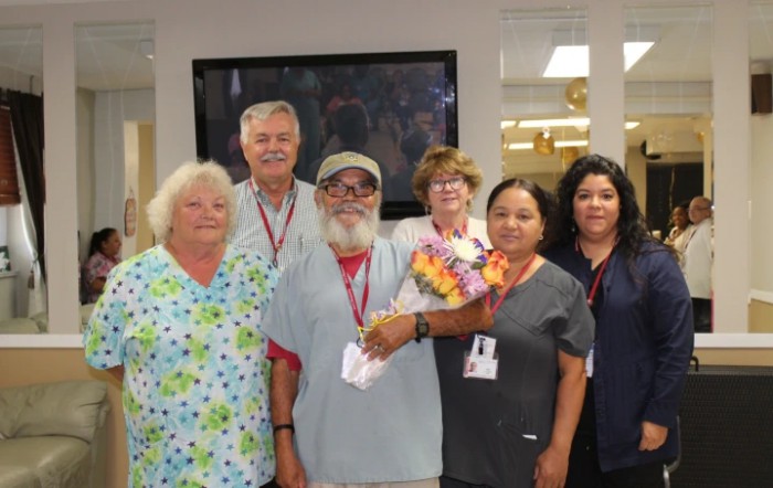 A group photo of staff members gathered together, smiling in a workplace setting.