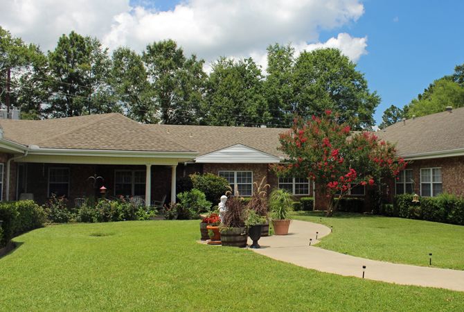 A suburban house with a well-maintained lawn and garden under a partly cloudy sky.