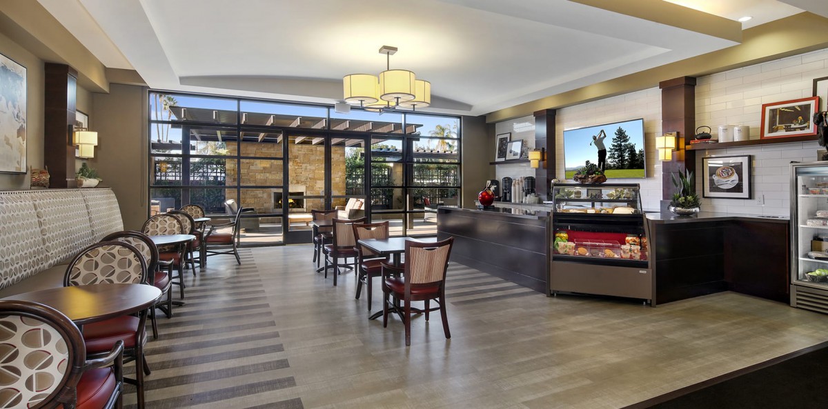 A modern cafe interior with tables, chairs, and a display counter.