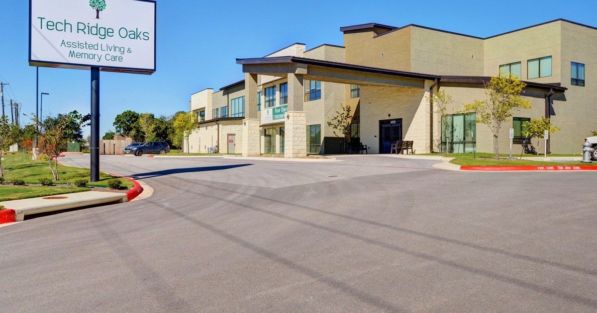 A commercial building with a parking lot and clear blue sky.