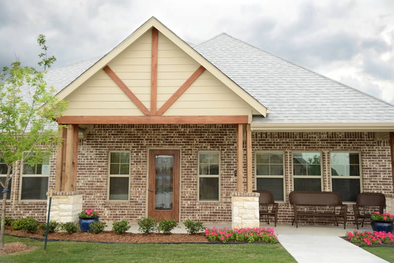 A cozy suburban brick house with a welcoming porch and well-maintained front yard.