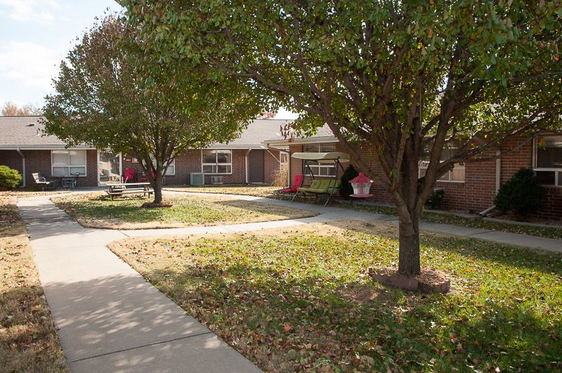 A suburban house with a front yard and trees in an autumn setting.