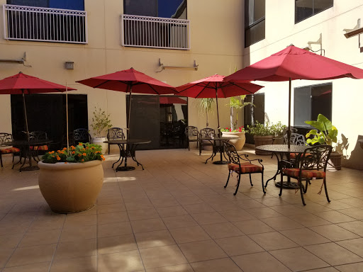 A serene outdoor patio space featuring red umbrellas and comfortable seating, perfect for relaxation.
