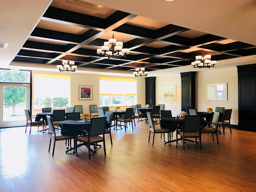 A spacious dining area featuring elegant chandeliers and warm wooden flooring.