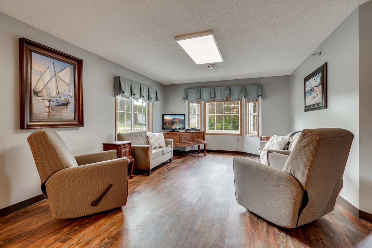 A cozy living room with plush armchairs and large windows, featuring hardwood floors and tasteful decor.
