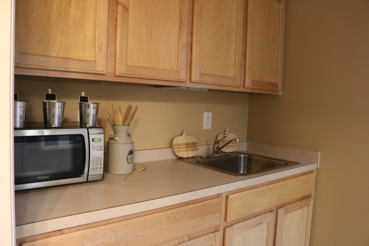 A kitchen countertop with wooden cabinets, a microwave, and a sink.