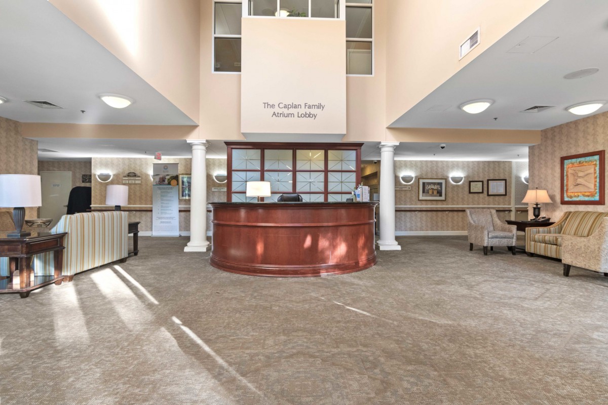 A spacious and well-lit reception area with a central desk and decorative columns.