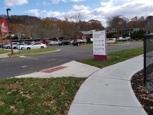 A view of a parking lot with signage and a sidewalk under a cloudy sky.