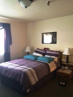 A cozy bedroom with a neatly made bed, two nightstands, and lamps.