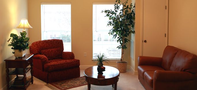 A cozy living room with two sofas, a round wooden coffee table, and a potted plant by the window.