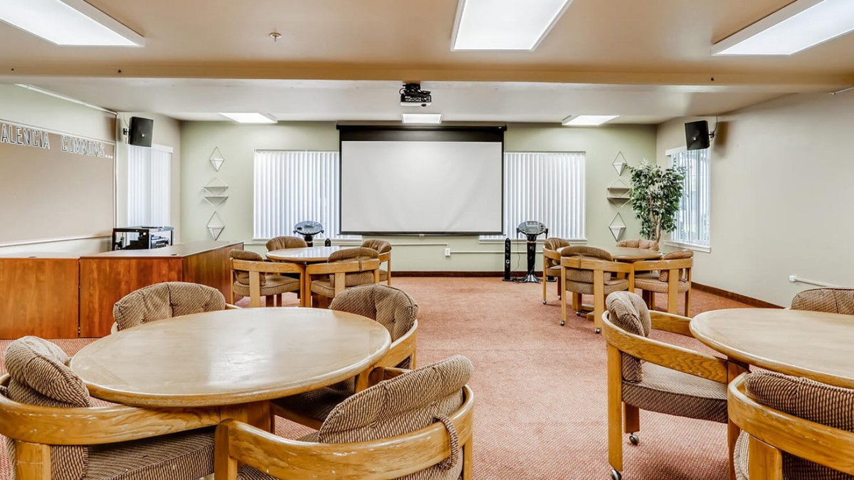 A conference room setup with round tables and a large projector screen.