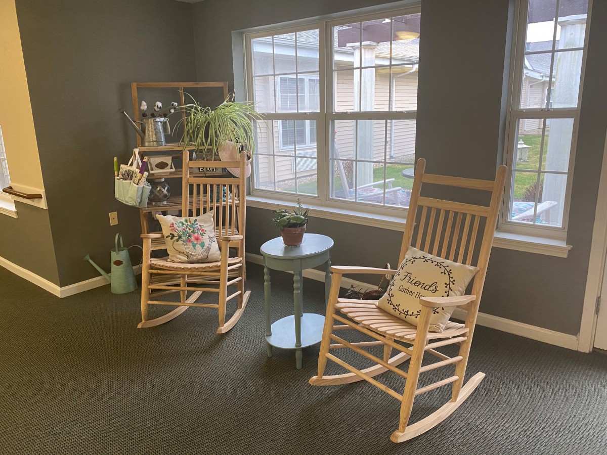 A cozy corner with rocking chairs and plants by the window.