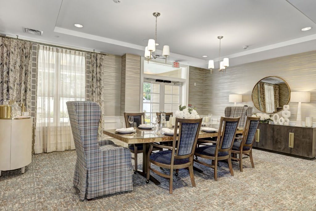 A beautifully designed dining room with a large wooden table, upholstered chairs, and elegant lighting fixtures.