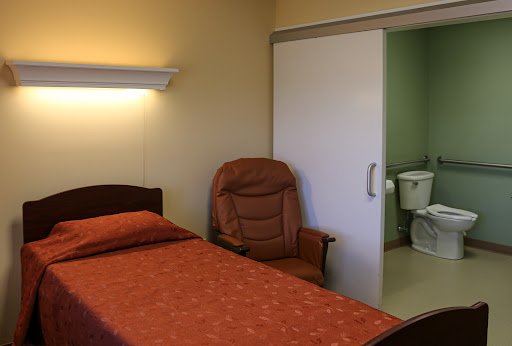 A simple bedroom with a bed, armchair, and an adjoining bathroom.