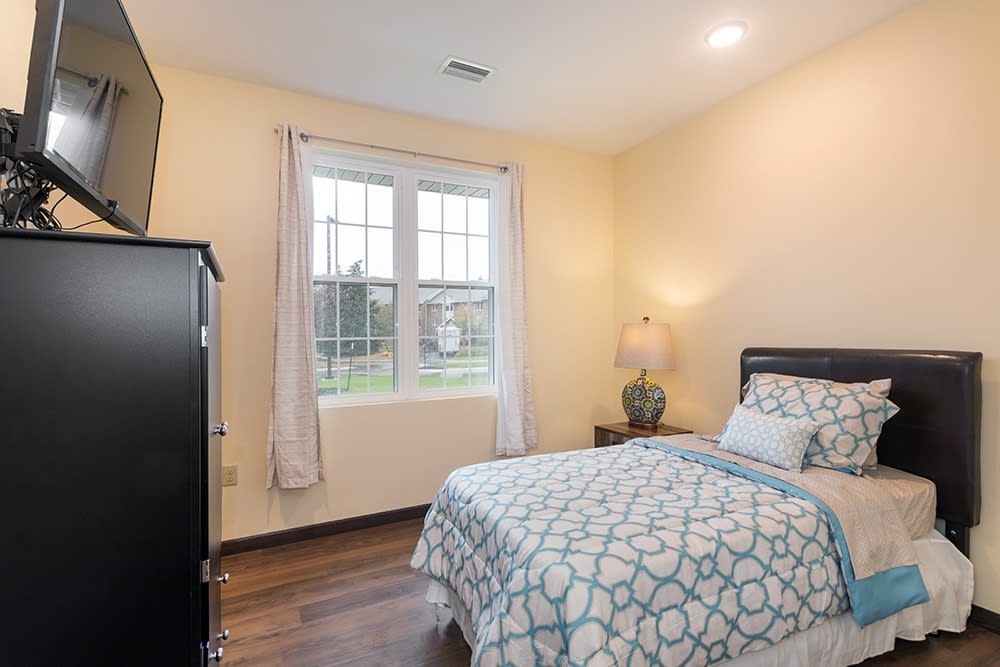 A cozy bedroom with a single bed, soft lighting, and a large window.