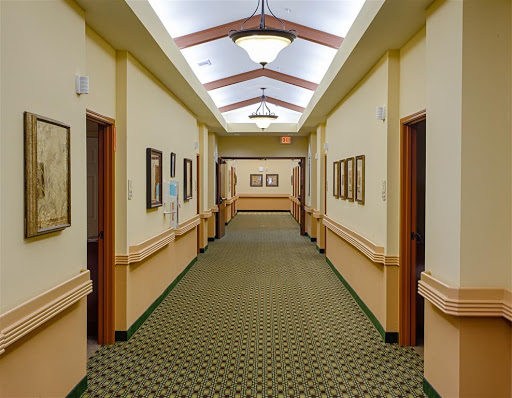 A well-lit hallway featuring framed artwork and patterned carpet.
