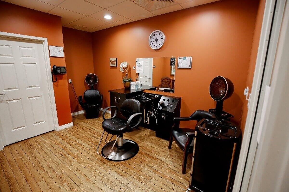 A cozy hair salon interior featuring styling chairs, mirrors, and a wall-mounted clock.
