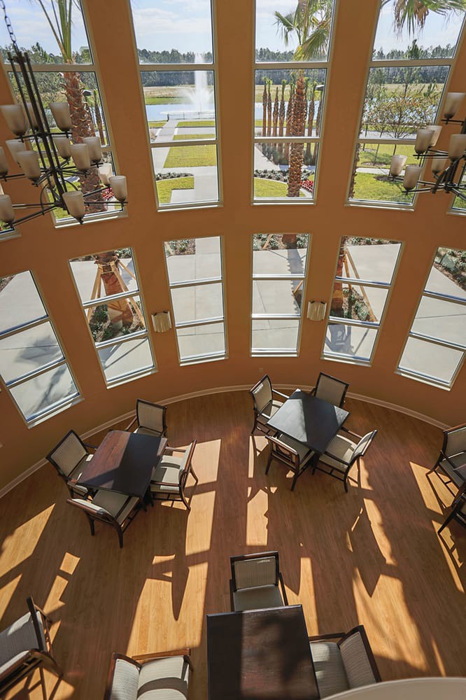 Cozy seating area with tables and chairs bathed in natural sunlight streaming through large windows.