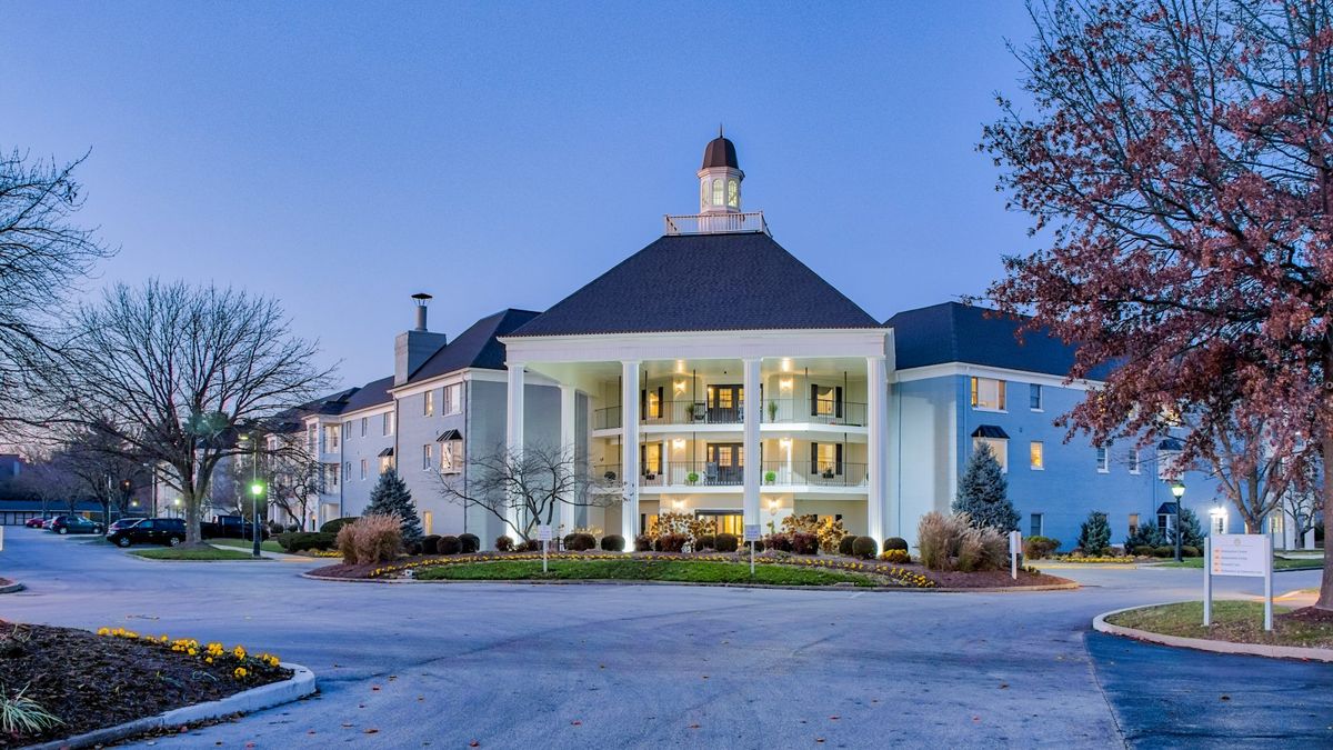 A grand hotel with lighted windows and a welcoming entrance at twilight.