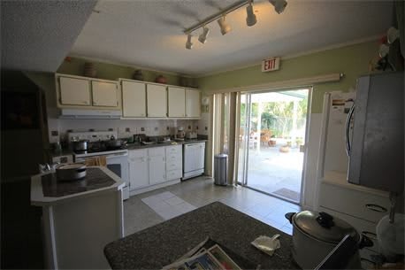 A modern kitchen with white cabinets and a sliding glass door leading outside.