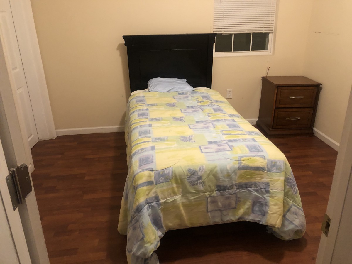 A simple bedroom with a single bed and nightstand.