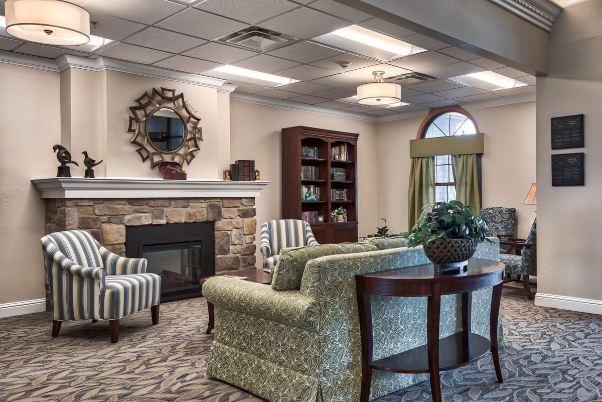 A cozy living room featuring a fireplace, elegant furniture, and a well-organized bookshelf.