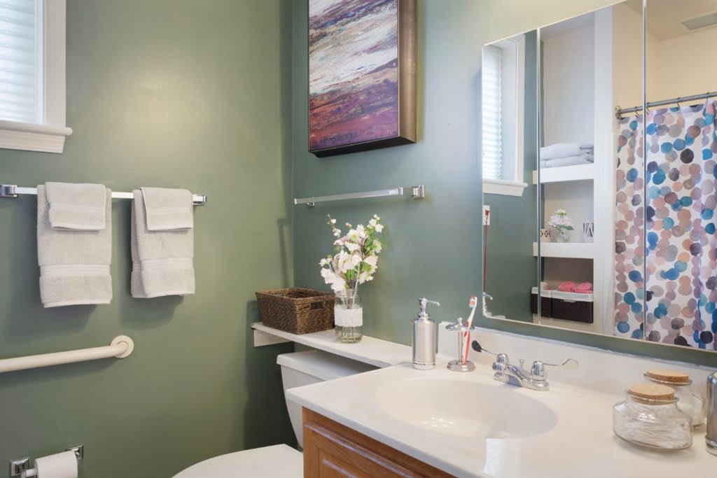 A neatly arranged bathroom with modern decor and a green accent wall.
