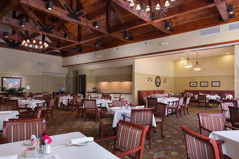 An elegant dining area featuring neatly arranged tables and chairs under beautiful chandeliers.