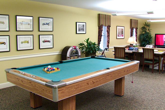 A well-lit recreation room featuring a pool table and wall decorations.