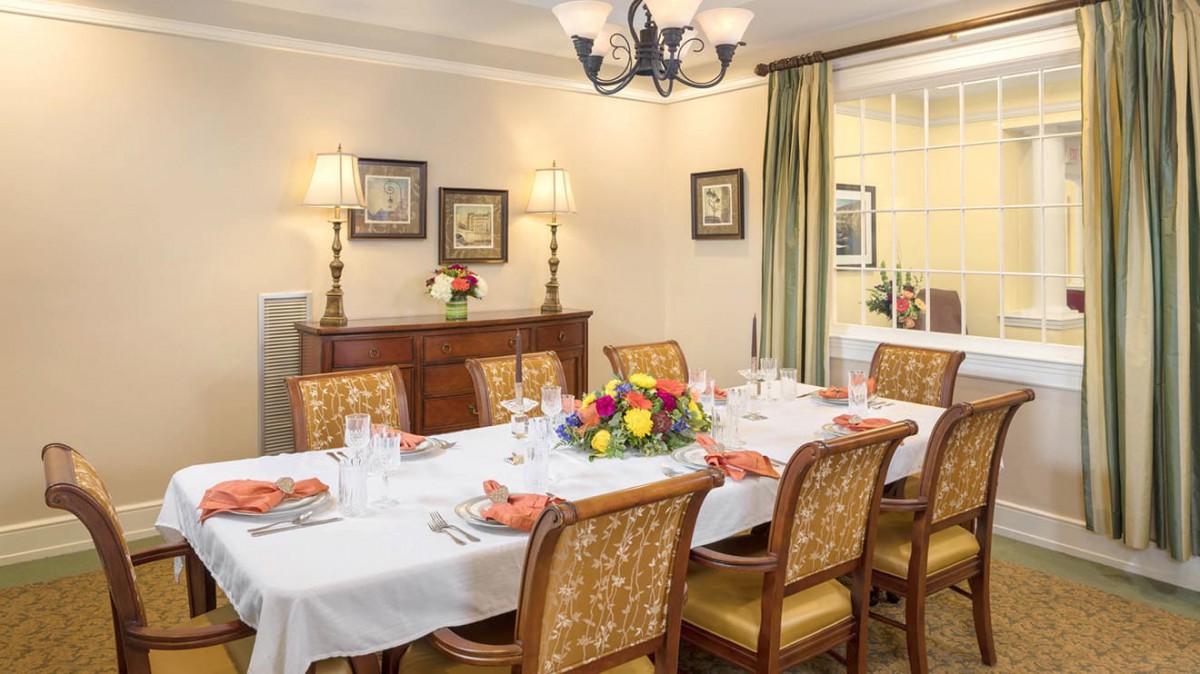 A elegantly set dining room table with floral centerpiece and warm decor.
