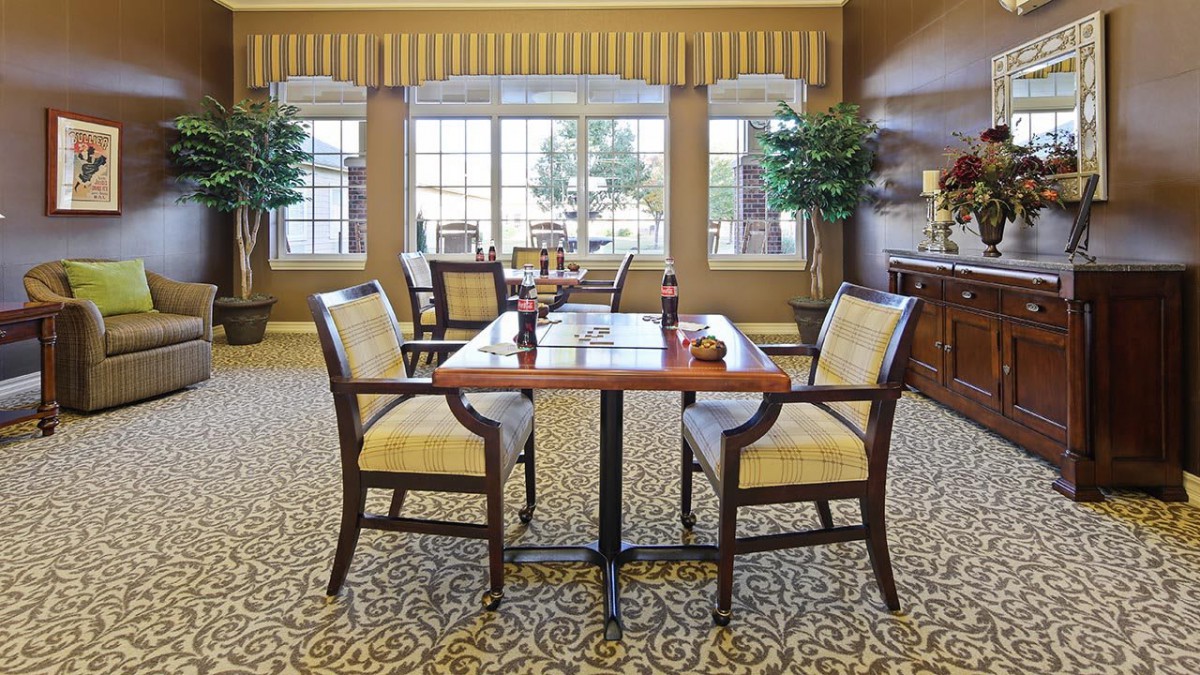 A well-decorated dining room with a wooden table, upholstered chairs, and large windows.