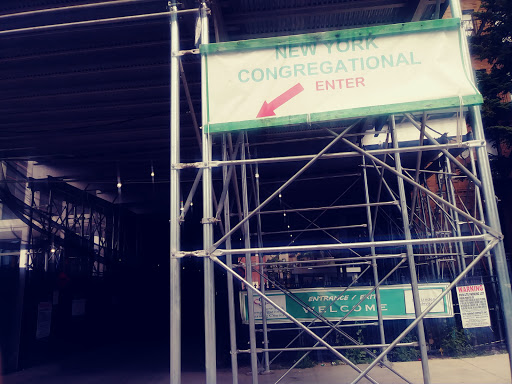 Construction site entrance with scaffolding and directional signage.