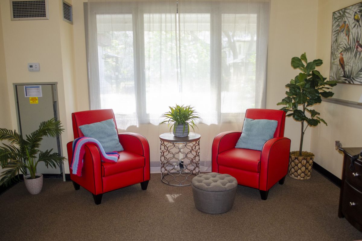 Cozy living room corner with two red armchairs and a side table, illuminated by natural light from the window.