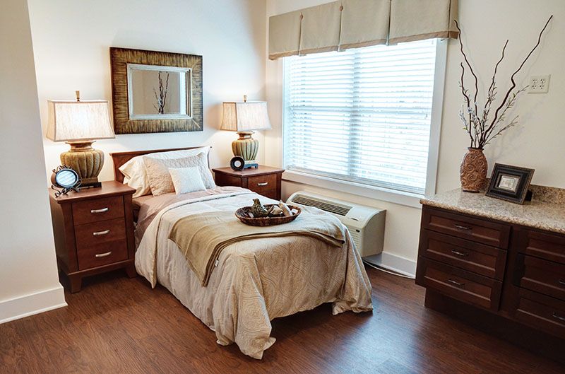 A cozy and well-decorated bedroom with a neatly made bed, two nightstands, and a large window.