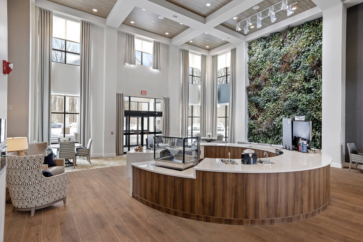 A modern lobby with high ceilings, a reception desk, and a vertical garden wall.