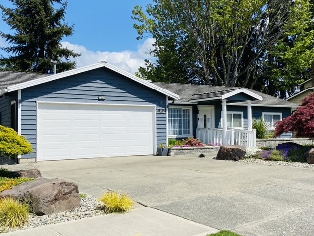A suburban single-story house with a driveway and attached garage on a sunny day.