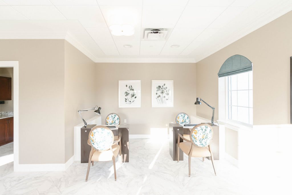A bright and minimalist office space with two desks, chairs, and lamps.