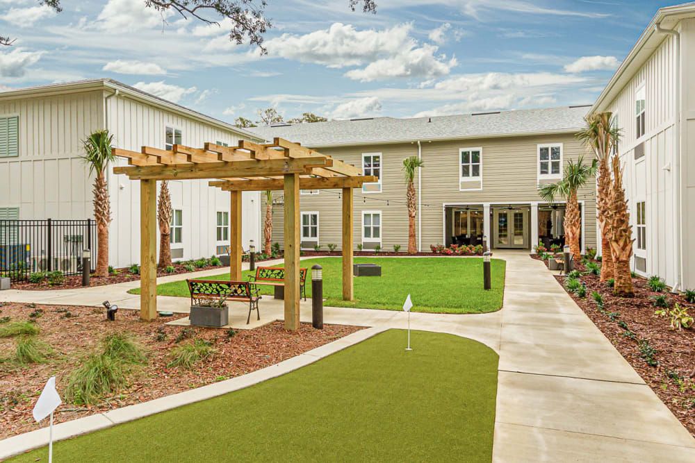 A beautifully landscaped courtyard with a wooden pergola and green lawn surrounded by a modern building.