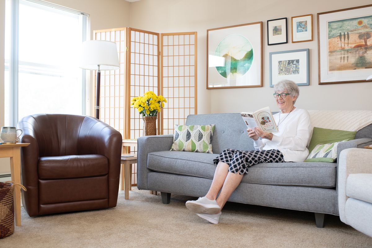 A person sitting on a sofa in a well-decorated living room, reading a book.