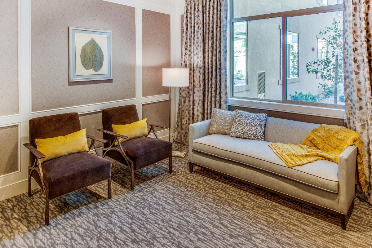 A well-furnished living room with a sofa, two chairs, a lamp, and decorative elements.