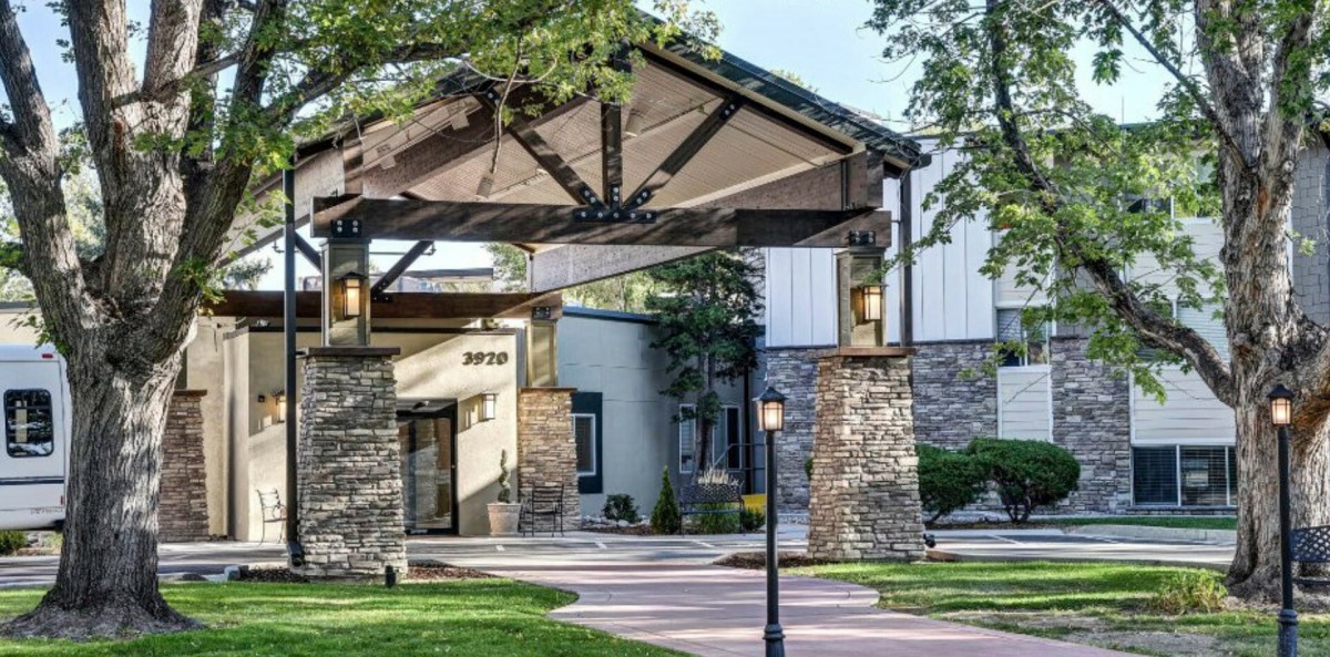 A scenic view of a building entrance with stone pillars and lush landscaping.